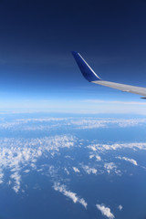 Obraz premium An airplane's wing over a blue and cloudy sky