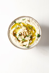 Classic hummus with herbs, olive oil in a vintage ceramic bowl. Traditional Middle Eastern cuisine. Light white background.