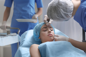 Plastic surgeon marking face of young woman prior to operation in clinic