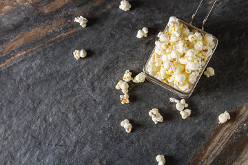 Salted popcorn in a cup. Dark background. Selective focus. Fast food for movies. Top view