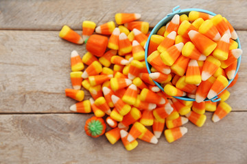 Bucket with tasty Halloween candies on wooden background