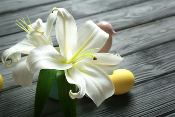 Beautiful Easter composition with lily and eggs on wooden table