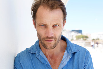 Fototapeta premium Close up cool older man leaning against wall and staring