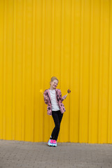 Portrait of a beautiful girl with red lips on a yellow background outdoors in summer