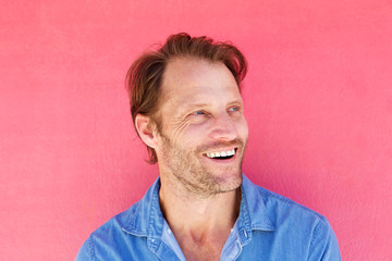 handsome man laughing against pink background
