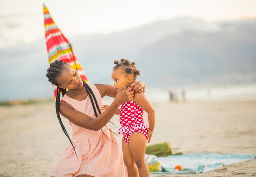 Beautiful mother caring for little girl at the beach