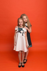 Two sisters in beautiful stylized dresses on a red background in the studio