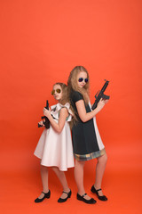 Fototapeta na wymiar Two girls in military dresses with arms in hand and sunglasses on red background