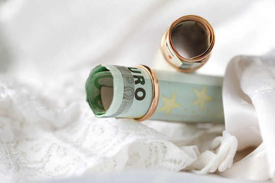 Wedding rings and money on a white bridal lingery background