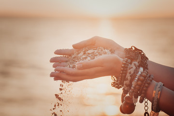 A woman with sand falling through her hands.summer background