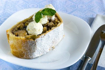 Homemade apple strudel with vanilla ice cream on white plate