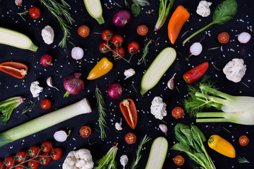 Colorful vegetables and spices on black background. Produce display. Organic healthy vegetarian foods. Farmers market layout. Top view.