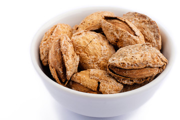 salted almonds in shell on white plate macro on white background