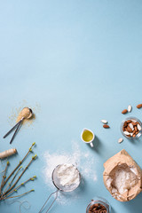 Baking ingredients over kitchen table. Flour, almonds, oil, sugar, cinnamon. Above view, copy space. 