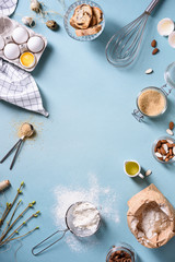Bakery background frame. Fresh cooking ingredients - egg, flour, sugar, butter, nuts over blue background. Spring cooking theme. Top view, copy space.