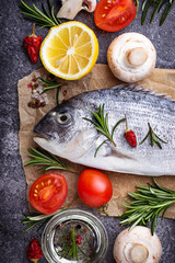 Uncooked dorado fish with rosemary and vegetables
