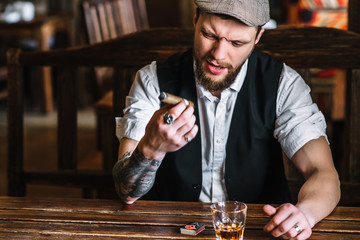 A young bearded man smoking a cigar in a pub
