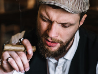 A young bearded man smoking a cigar in a pub