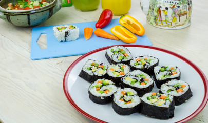 Home made vegan sushi rolls and vegetables on the kitchen table