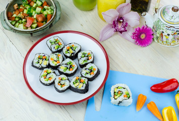 Home made vegan sushi rolls, salad and vegetables on the kitchen table