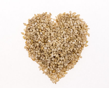 Sesame seeds in the form of heart on white background