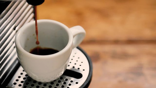 pour coffee with coffee maker in a white cup on a wooden table in the kitchen at the breakfast