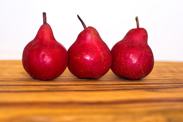 Closeup of three organic red pears on a wooden board
