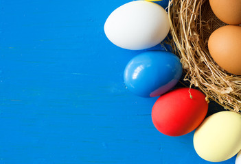 Red, blue, white eggs ( As flag of some countries ) in nest on rustic wooden background, selective focus image. Happy Easter Card - space for text. 