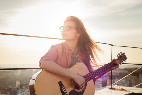 young beautiful woman with a guitar on the roof