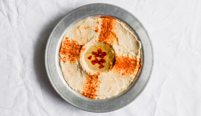 Hummus with paprika, olive oil, and pomegranate seeds against white background. Selective focus.