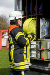 Feuerwehrfrau holt einen Schlauch vom Löschfahrzeug