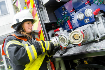 Fototapeta premium Feuerwehrfrau schließt Schlauch an die Pumpe an
