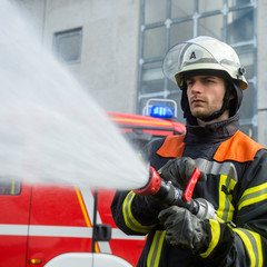 Fototapeta premium Feuerwehrmann beim Löschen mit einem Schlauch
