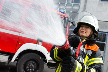 Naklejka premium Junge Feuerwehrfrau löscht ein Feuer