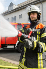Fototapeta premium Feuerwehrmann beim Löschen mit einem Schlauch