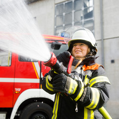 Obraz premium Junge Feuerwehrfrau löscht ein Feuer