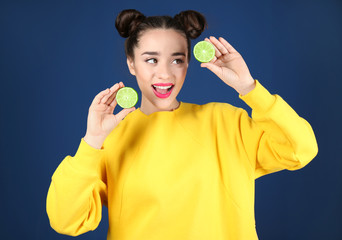 Beautiful young woman with lime on dark blue background