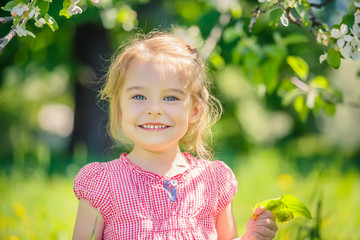 Happy little girl playing in spring apple tree garden