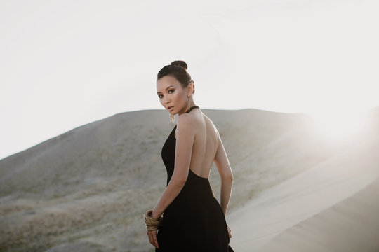 Woman in a black dress on a dune of desert