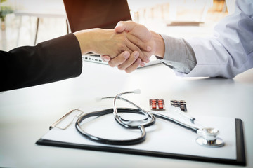 Male doctor in white coat shaking hand to female colleague