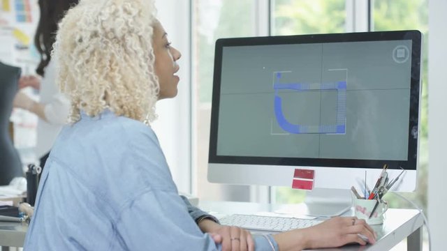  Jewelry designer at her desk working on computer with 3D modeling software. 