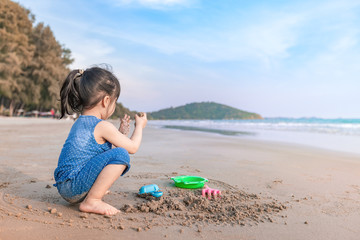 little girl 2-3 years plays on the beach in sunset