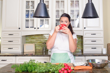 Attractive smiling woman making salad in her sunny kitchen