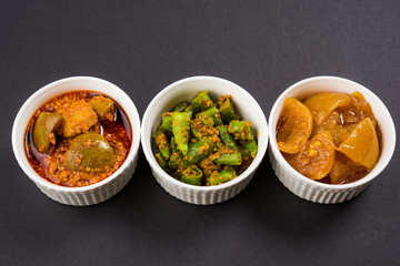 Group photograph of indian pickles like mango pickle , lemon pickle and green chilli pickle, sarved in ceramic bowls, selective focus © StockImageFactory