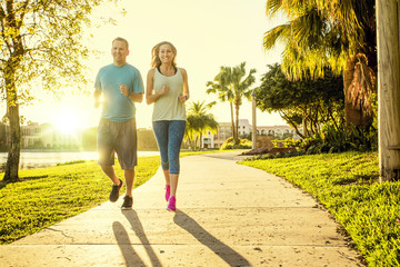 Man and woman exercising and jogging together at the park. Happy and smiling as they run along the...