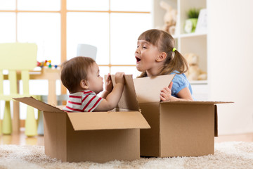 Baby brother and child sister playing in cardboard boxes