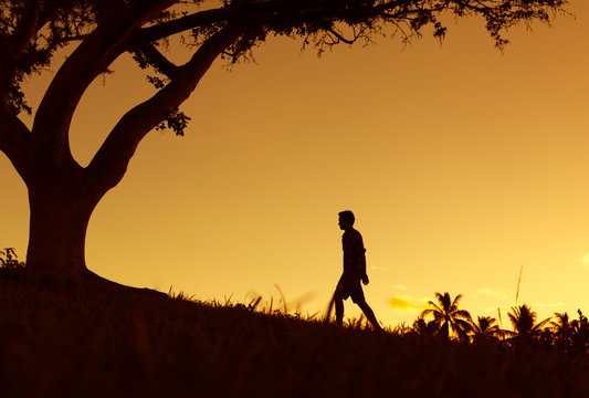 Silhouette of young man walking alone in the park. 
