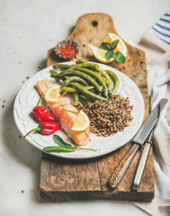 Healthy protein rich dinner plate. Oven roasted salmon fillet with multicolored quinoa, chilli pepper and poached green beans on rustic wooden board over grey marble background. Clean eating food