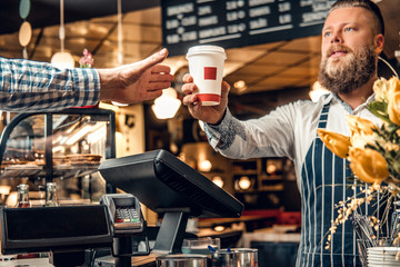 Fototapeta na wymiar A man selling coffee to a consumer in a coffee shop.