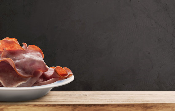 Ham slice in white dish, on wooden desk and black wall backgrounds, with copy space